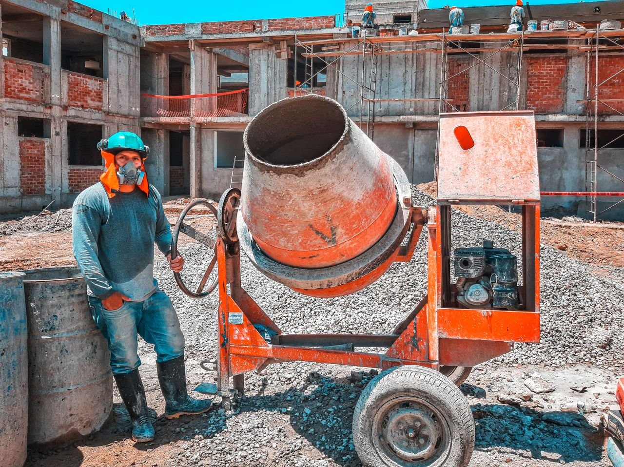Crafting Captivating Headlines: Your awesome post title goes here A construction worker operating a concrete mixer at an active building site, emphasizing safety gear.